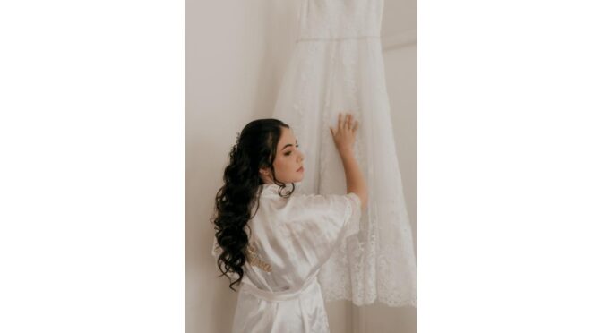Bride admiring an A-line lace wedding dress hanging in an elegant room