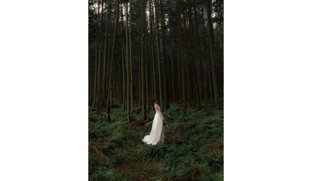 Bride wearing a simple sheath wedding dress standing in a forest