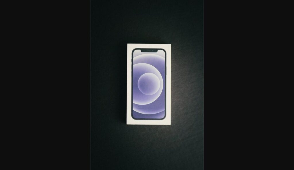 Purple iPhone 12 retail box on a dark surface