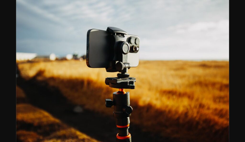 iPhone mounted on a tripod in a golden wheat field, set up for steady photography
