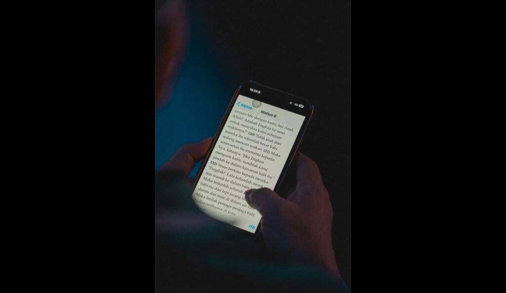 Close-up of a hand holding an iPhone with large accessibility text enabled