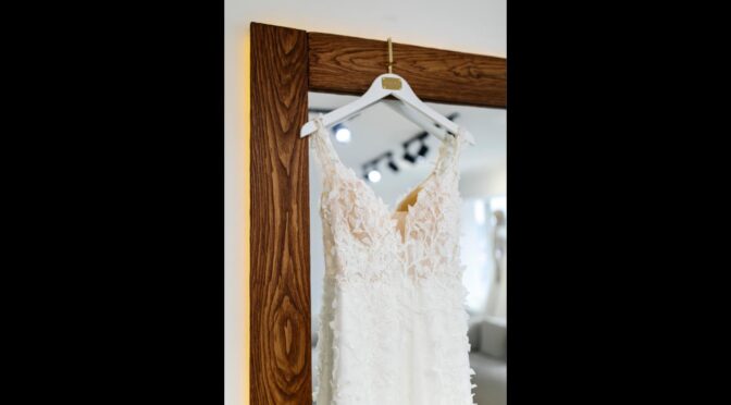 Wedding dress hanging on a wooden mirror frame in a bridal boutique