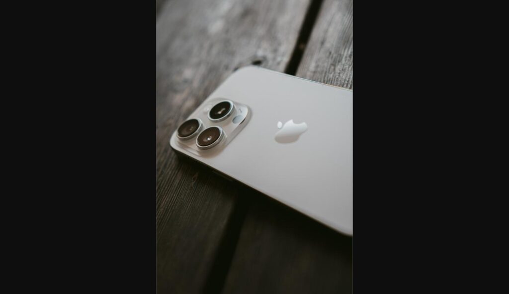 Close-up of an iPhone camera module and Apple logo on a wood surface